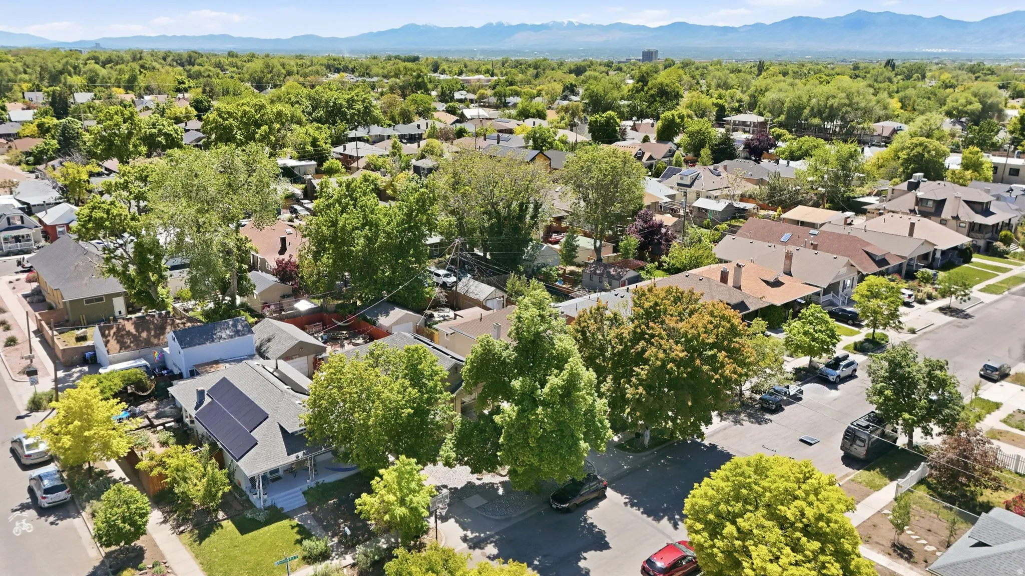 Aerial perspective showcasing a residential area with mature trees and mountain scenery