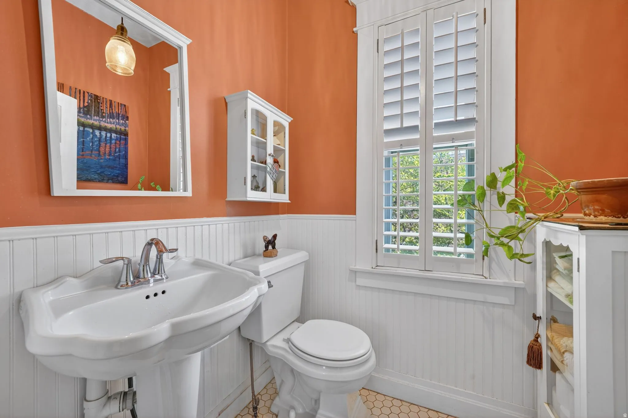 Pedestal sink with chrome faucet, white beadboard wainscoting, and hexagonal tile flooring