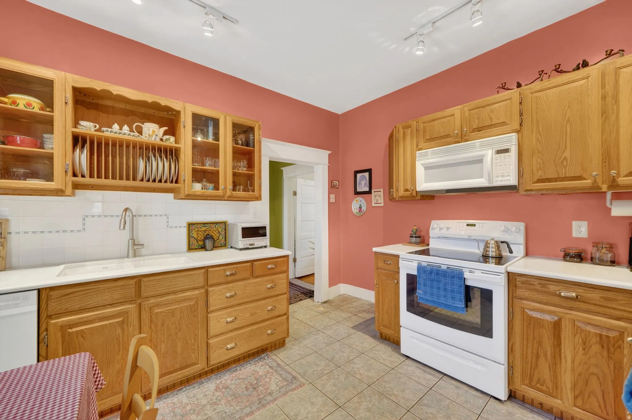 Kitchen featuring light wood cabinetry, white countertops, tile flooring, and a white tile backsplash