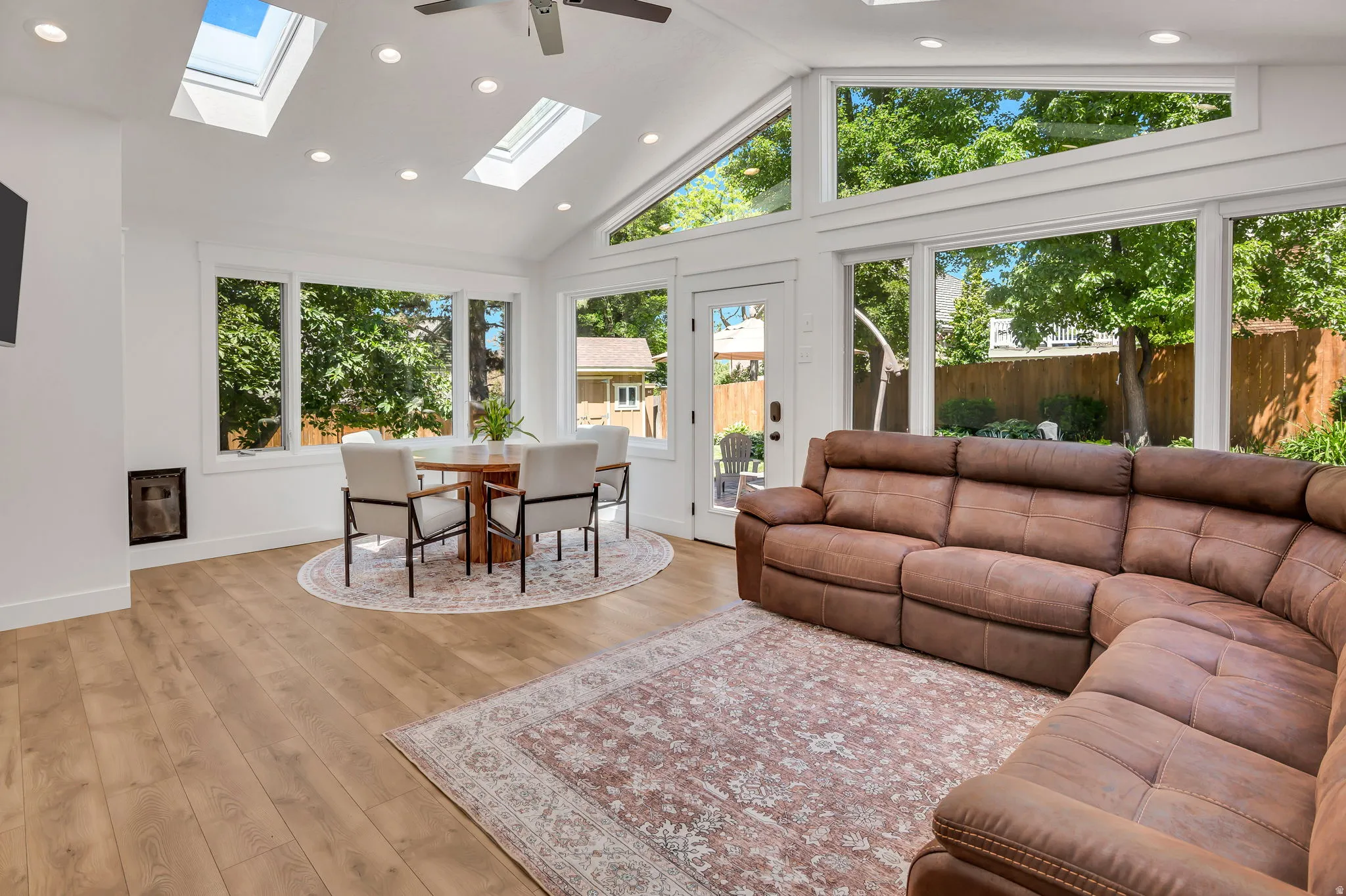 Open-concept living space with vaulted ceilings, skylights, recessed lighting, wood-finish flooring, and expansive windows