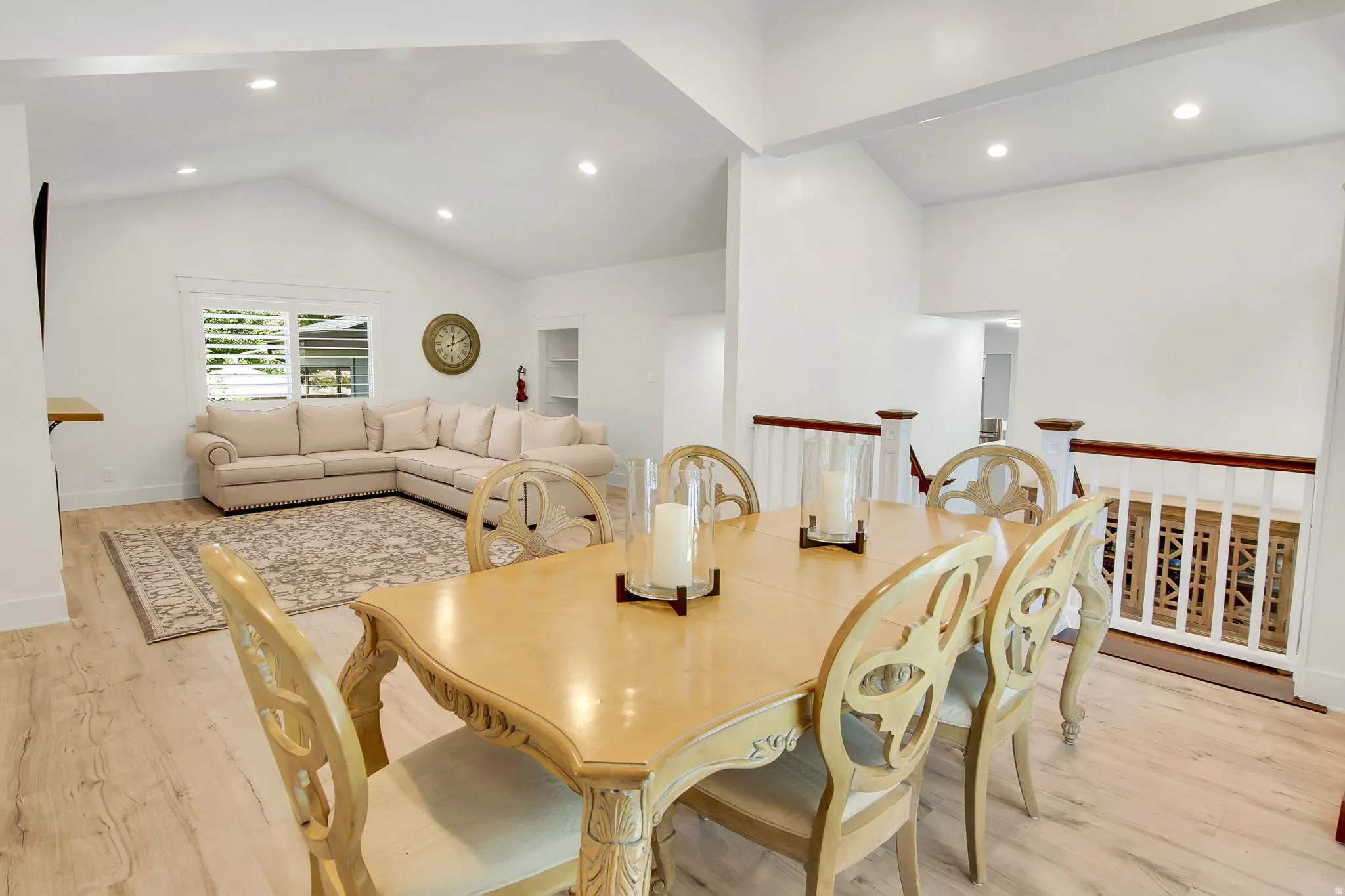 Open-concept dining and living areas featuring vaulted ceilings, recessed lighting, and wood-finish flooring