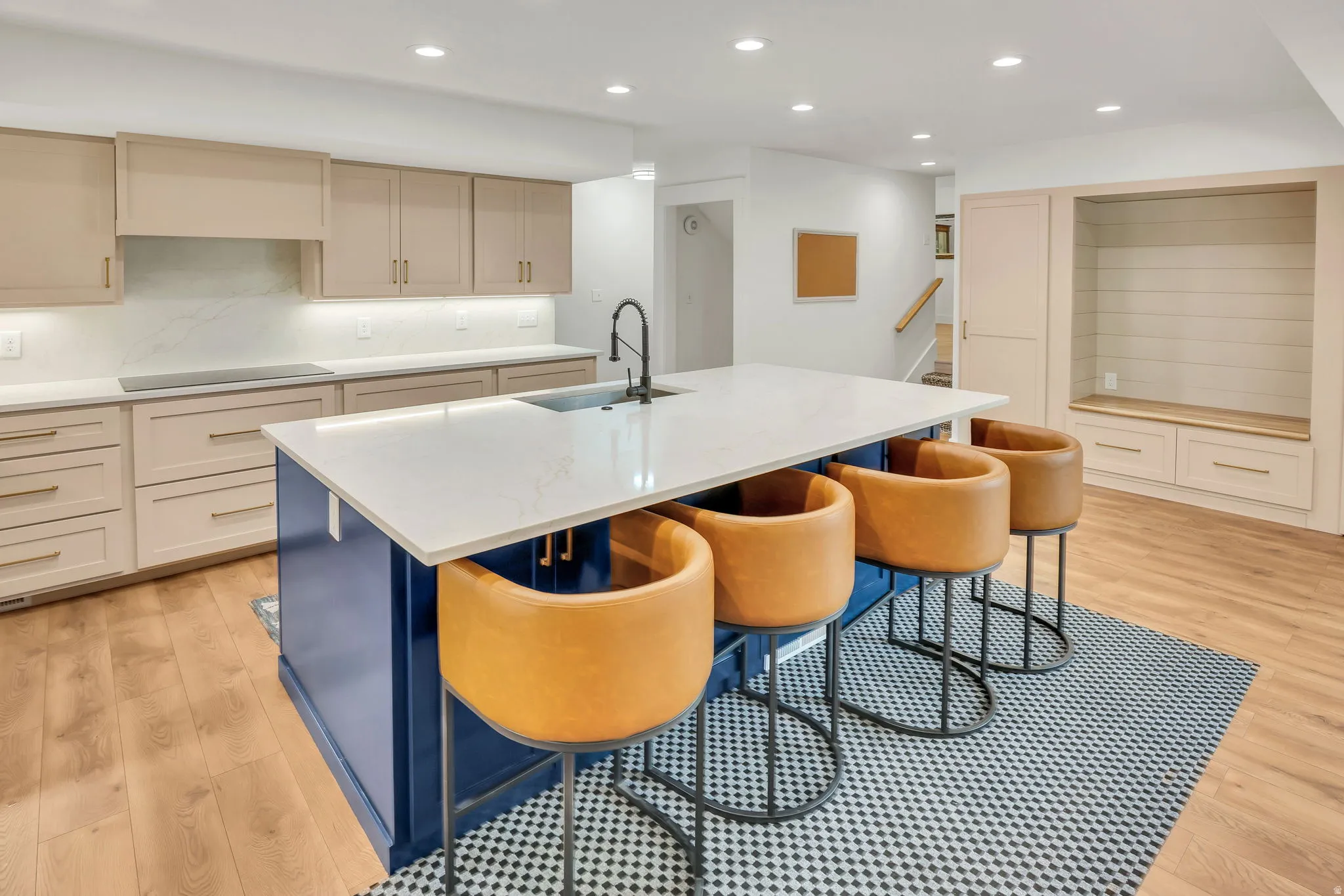 Kitchen island with a white countertop and integrated sink, complemented by light wood-finish flooring
