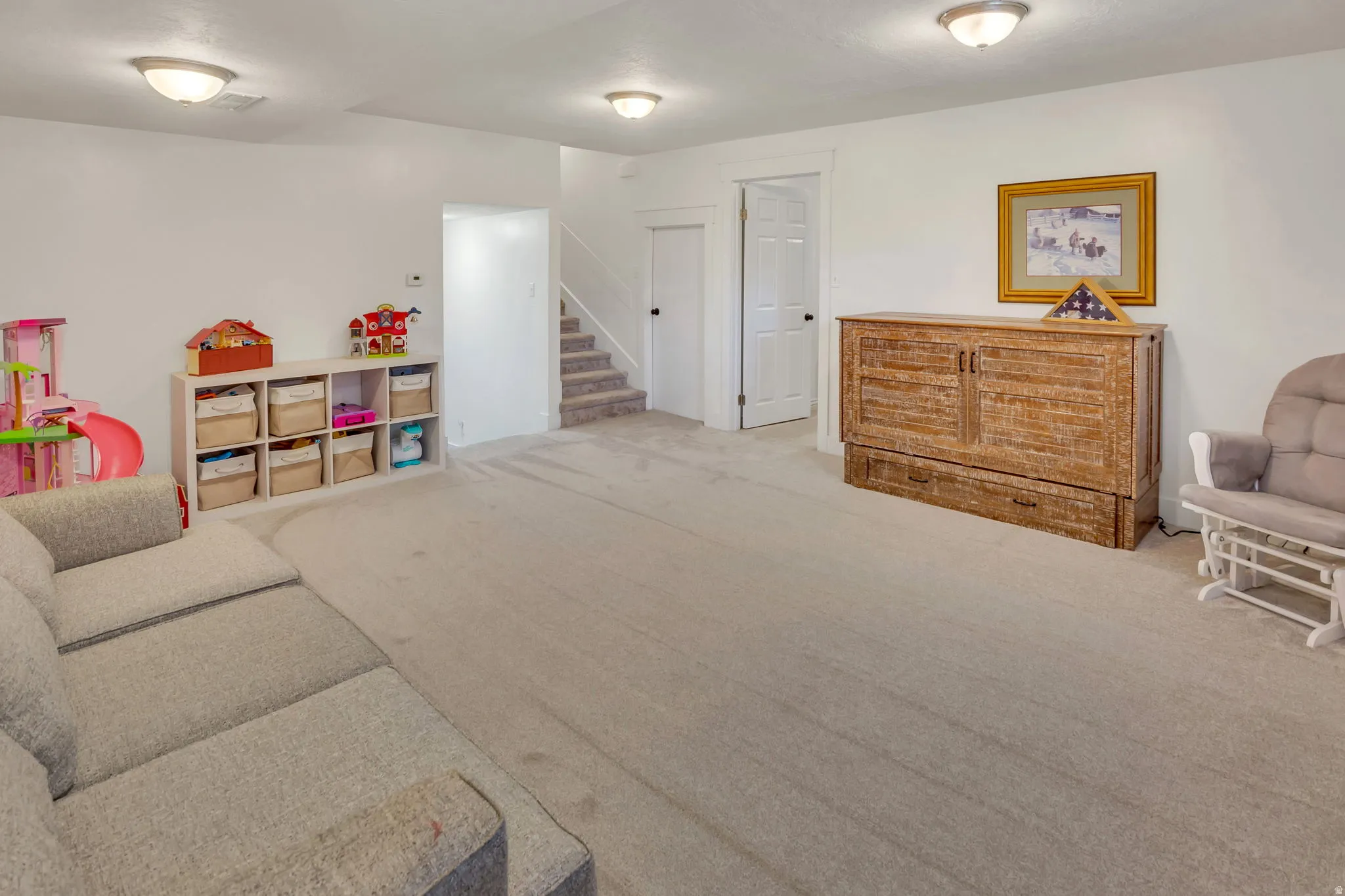 Spacious room featuring light-colored carpeting, white walls, and flush-mount ceiling lighting fixtures