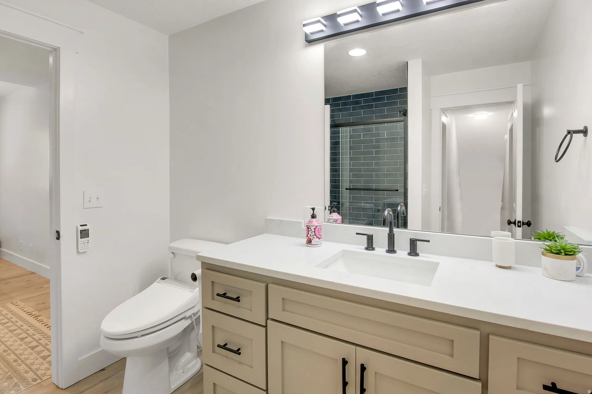 Bathroom featuring a light-toned vanity with black hardware, white countertop, and integrated sink