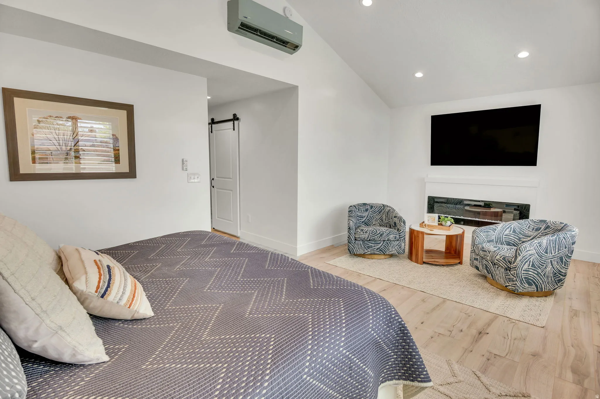 Vaulted ceilings with recessed lighting illuminate wood-finish flooring