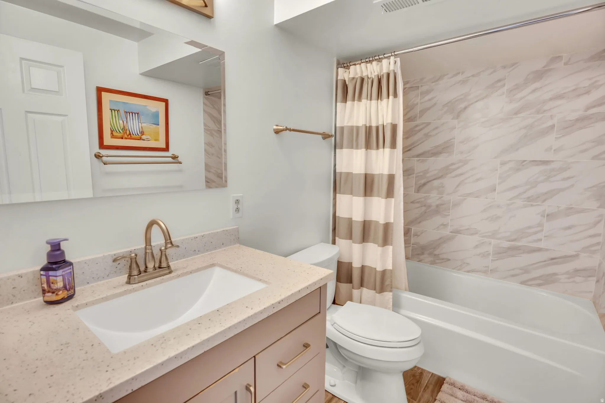 Bathroom vanity with a light-toned countertop and an integrated sink, featuring a polished brass faucet