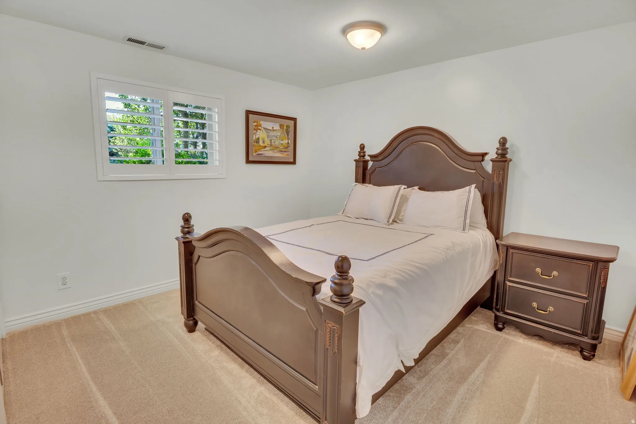 Room featuring neutral-toned carpeting, white walls, and a window with white plantation shutters