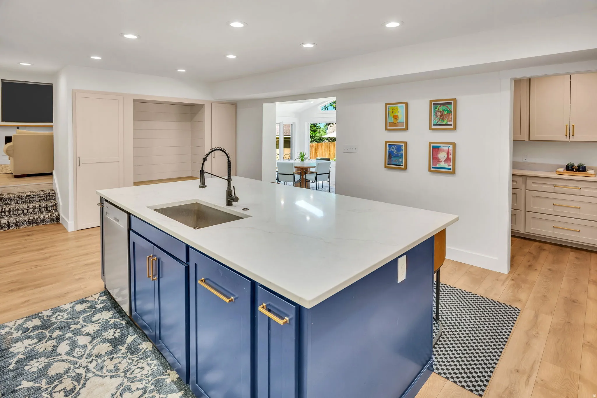 Kitchen island with a white countertop and integrated sink, featuring a matte black gooseneck faucet, blue cabinetry, and gold-tone hardware