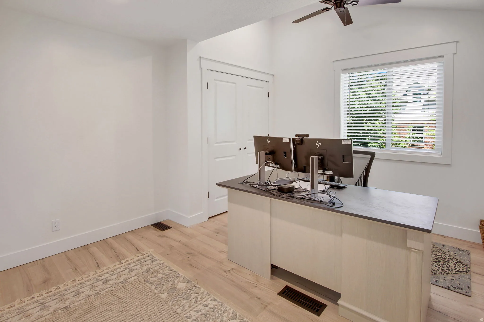 Bright room featuring light wood-finish flooring, white walls, and a window with blinds