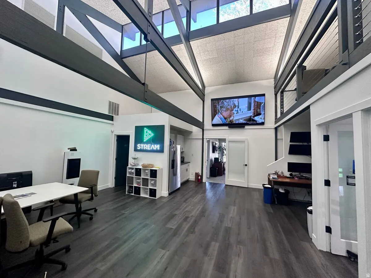 Vaulted ceiling with exposed beams, wood-finish flooring, and upper-level interior balcony with cable railing