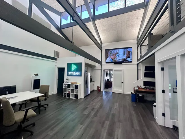 Vaulted ceiling with exposed beams, wood-finish flooring, and upper-level interior balcony with cable railing