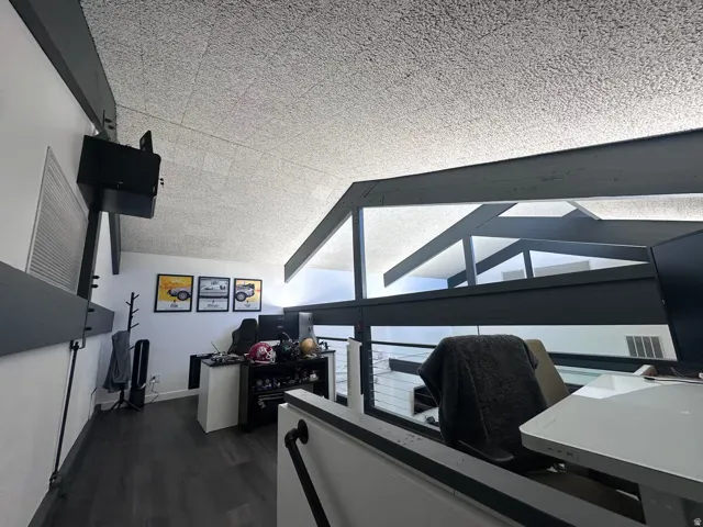 Loft area featuring exposed dark-finish beams and a textured ceiling