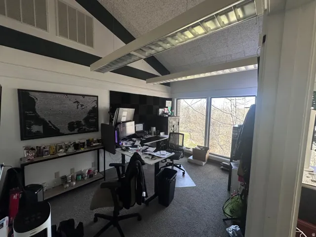 Vaulted ceiling with exposed beams, multiple transom windows, and a full wall of picture windows