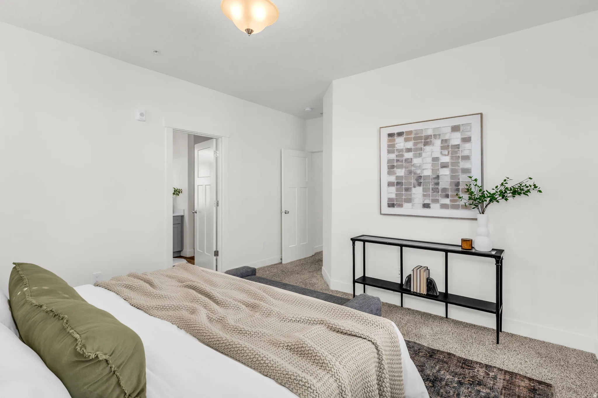 Neutral-toned bedroom featuring light gray carpeting, white painted walls, and a semi-flush mount ceiling light fixture