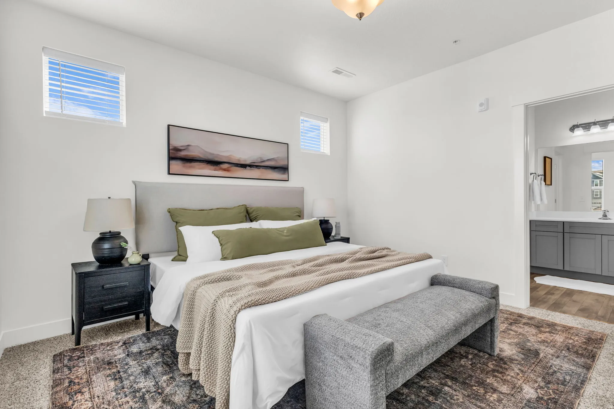 Carpeted bedroom featuring a built-in light fixture, white walls, and two elevated windows