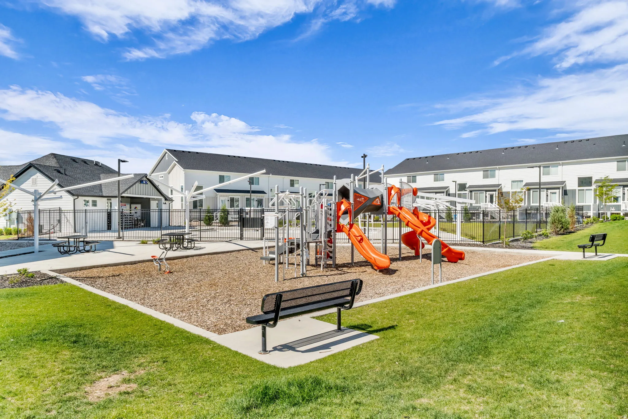 Outdoor recreational area featuring a playground with slides and climbing structures, surrounded by a wood chip surface