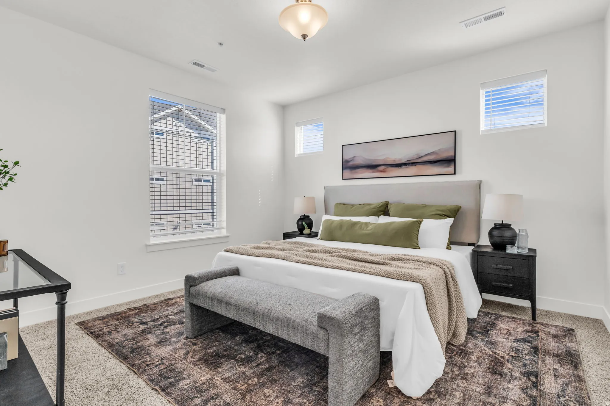 Bedroom featuring white walls, carpet flooring, a ceiling-mounted light fixture, and multiple windows with blinds