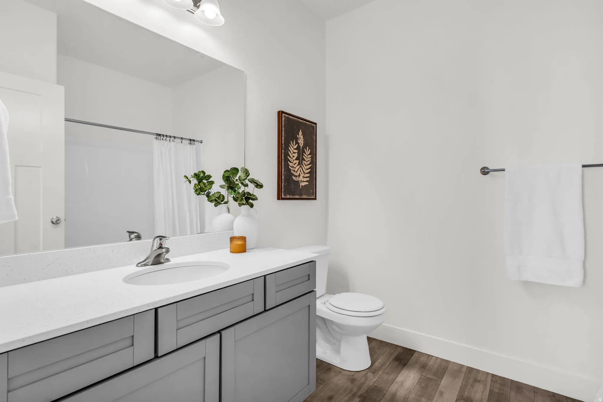 Bathroom vanity featuring a light gray shaker cabinet, white solid surface countertop, and an integrated sink with a chrome faucet