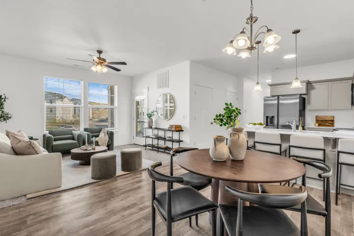 Open-concept living space featuring wood-finish flooring, a contemporary kitchen island with pendant lighting, white cabinetry, and stainless steel appliances