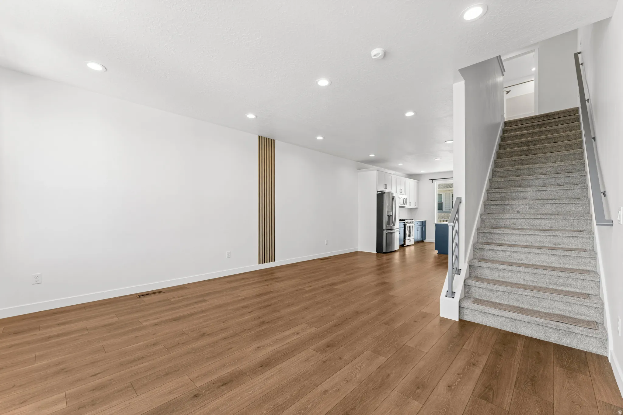 Open-concept living space with wood-finish flooring, recessed lighting, and a white baseboard trim