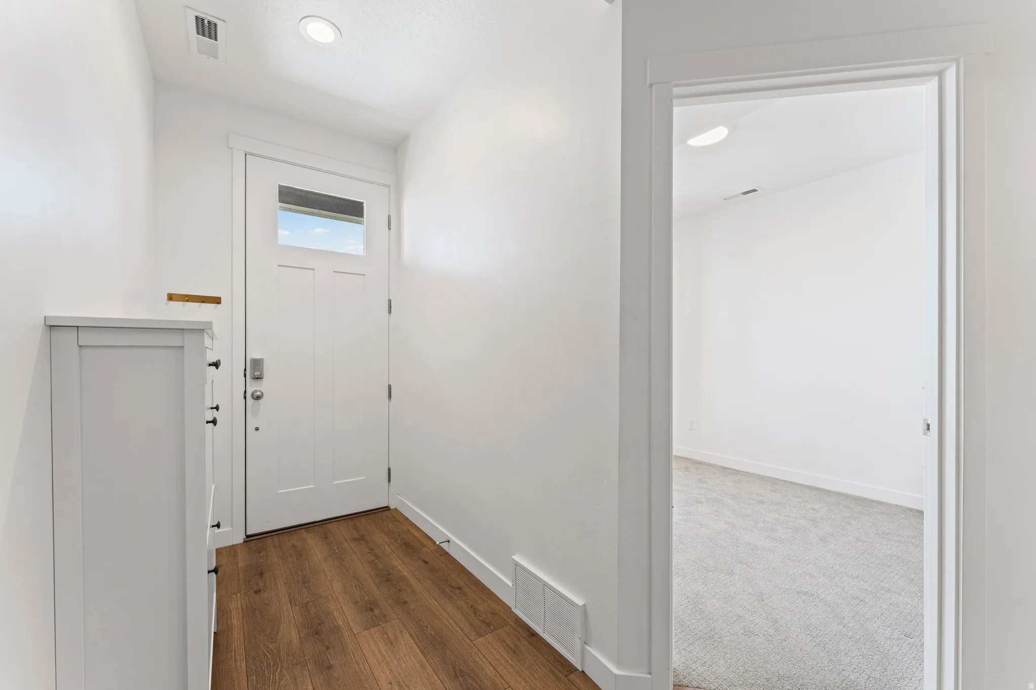 Entryway featuring wood-finish flooring, a white paneled door with a rectangular window, and a recessed ceiling light