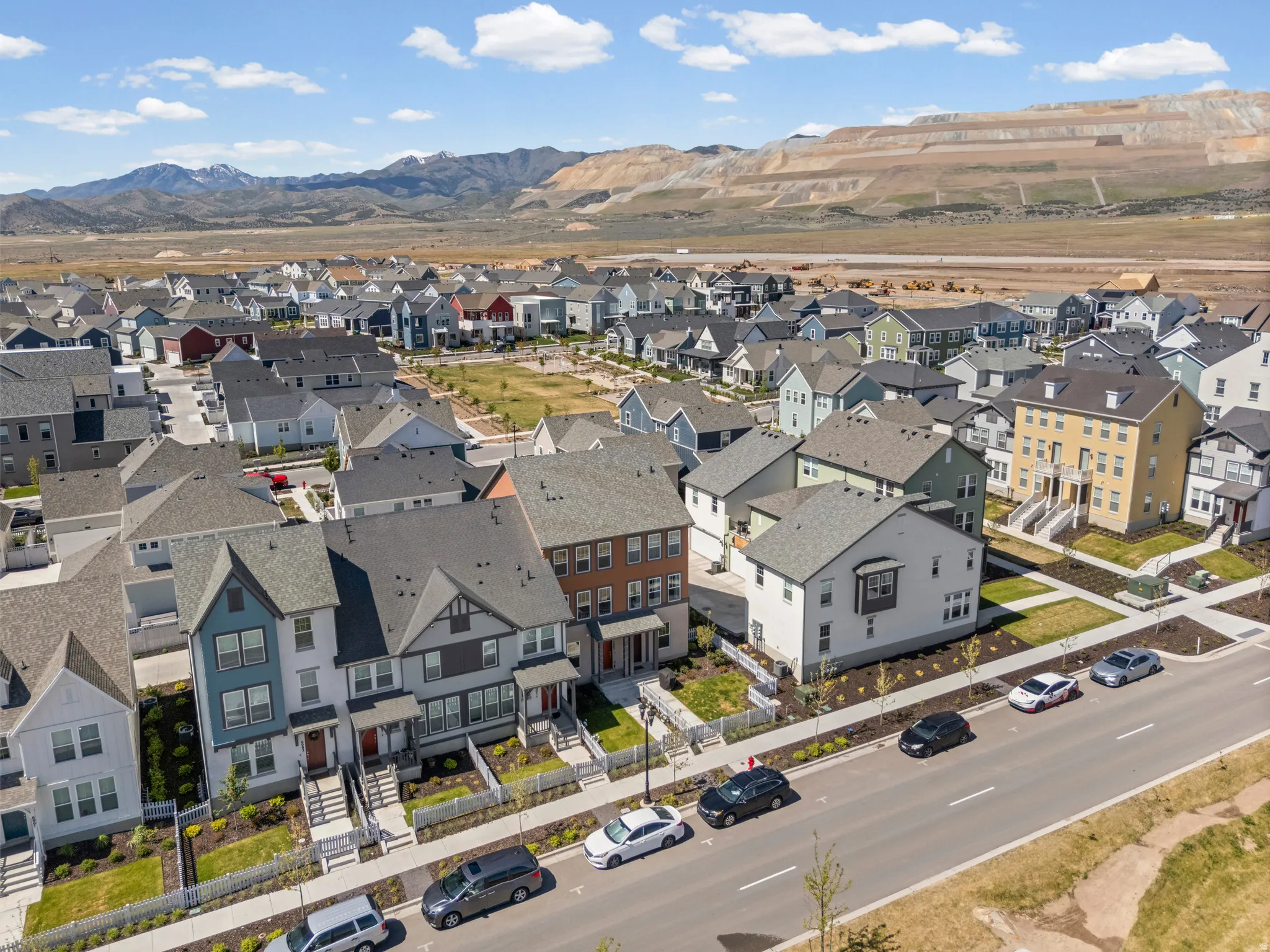 New construction residential streetscape featuring diverse architectural styles and a mountain backdrop