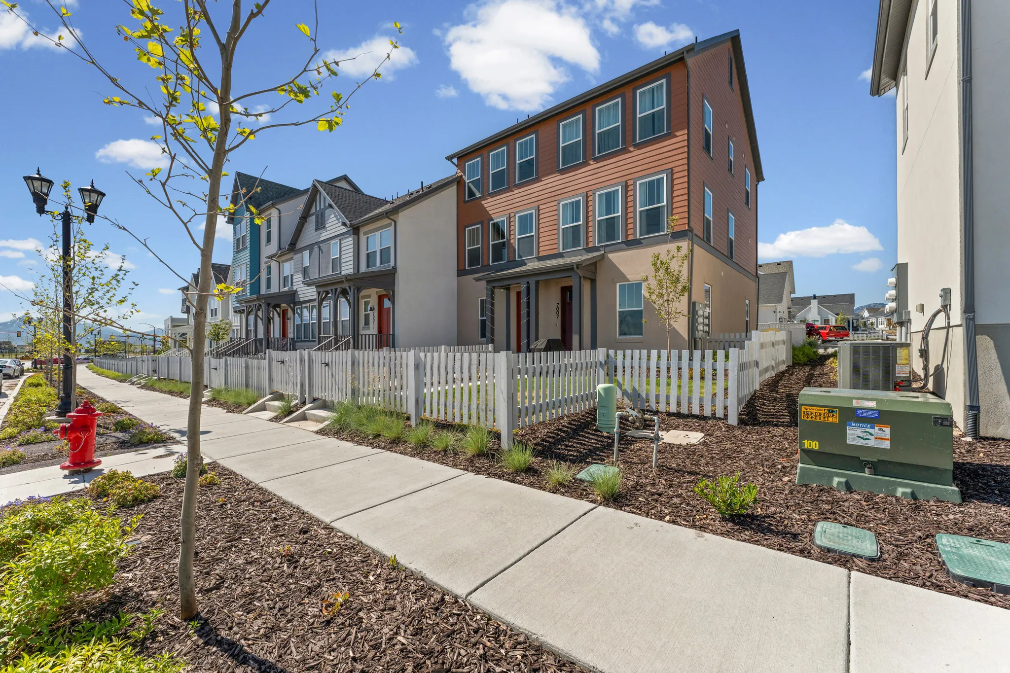 Contemporary townhome with a multi-story facade, white picket fence, and a private entry porch