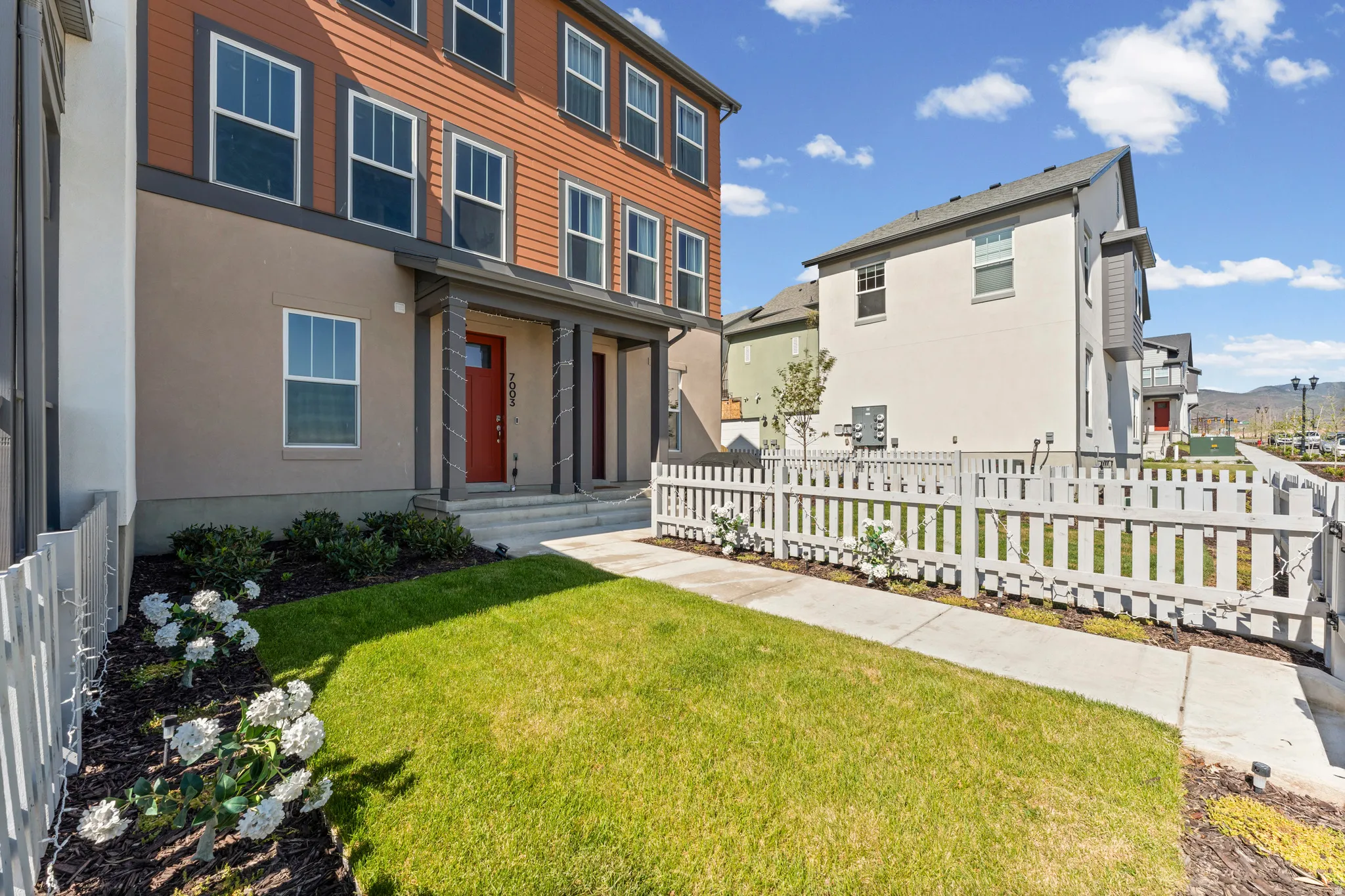 Three-story exterior featuring a contrasting brown siding and light tan stucco facade