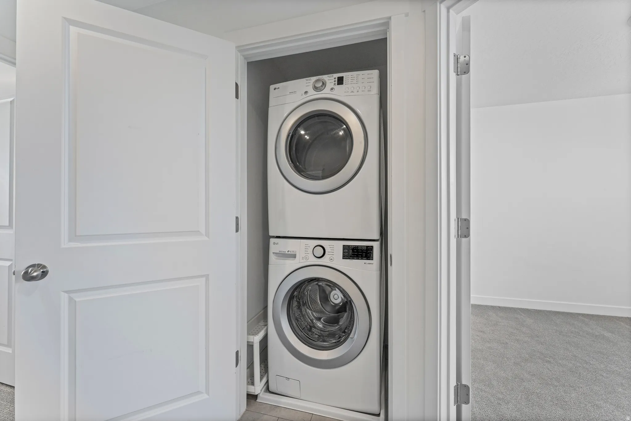 Built-in laundry closet featuring a stacked washer and dryer unit, front-loading appliances, and convenient access