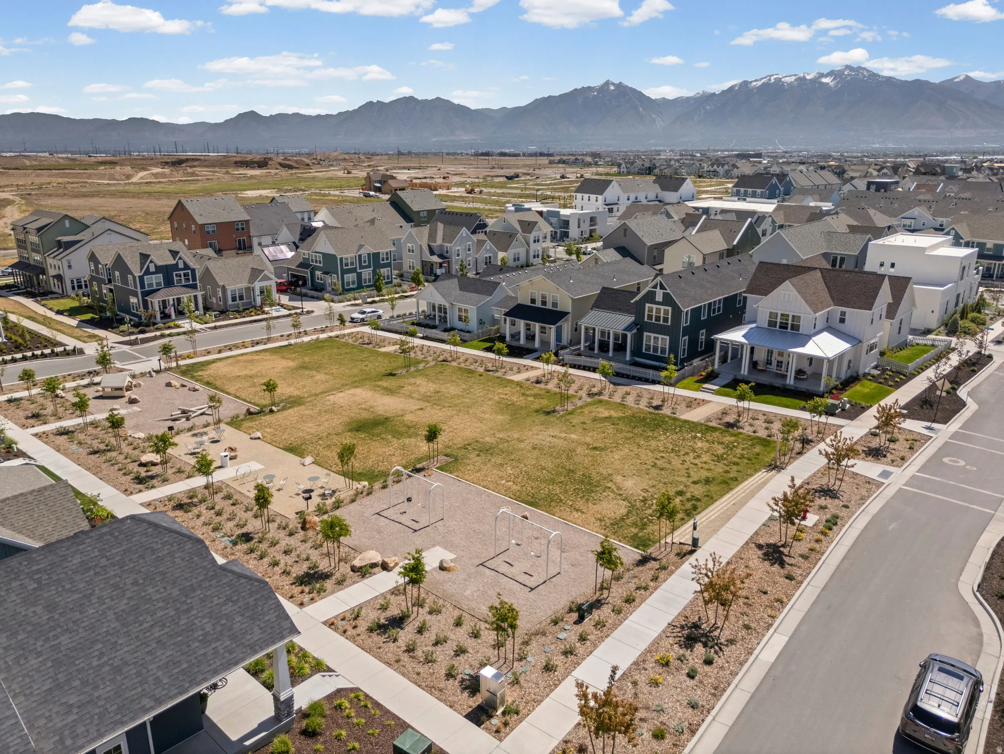 Community green space featuring a manicured lawn, playground area, and mature landscaping