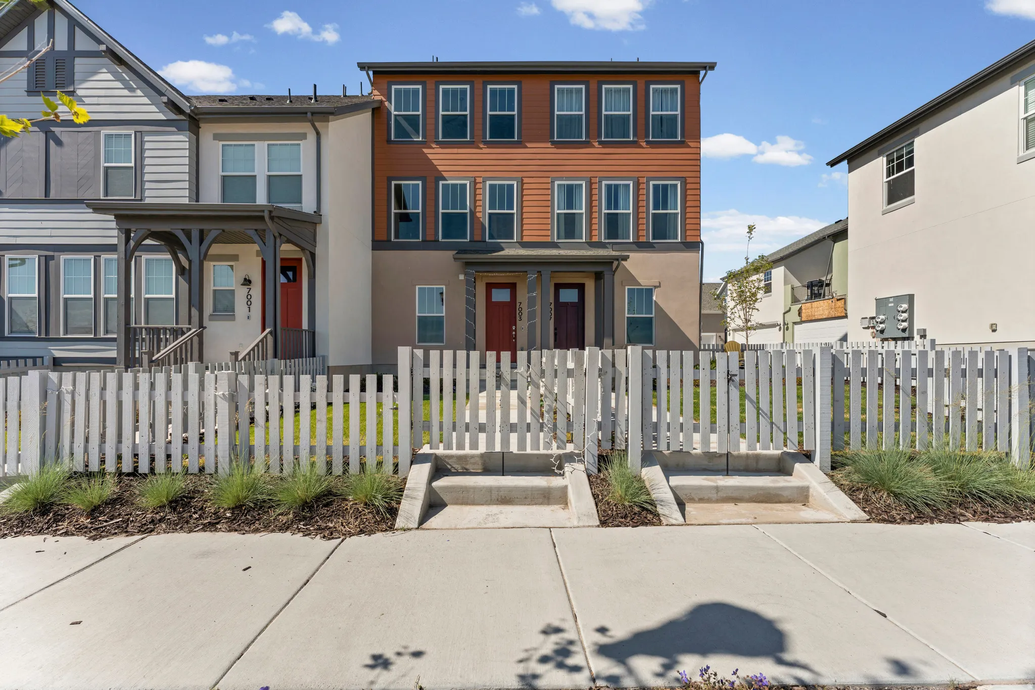Contemporary multi-level townhome featuring a warm color palette with wood-look siding accents