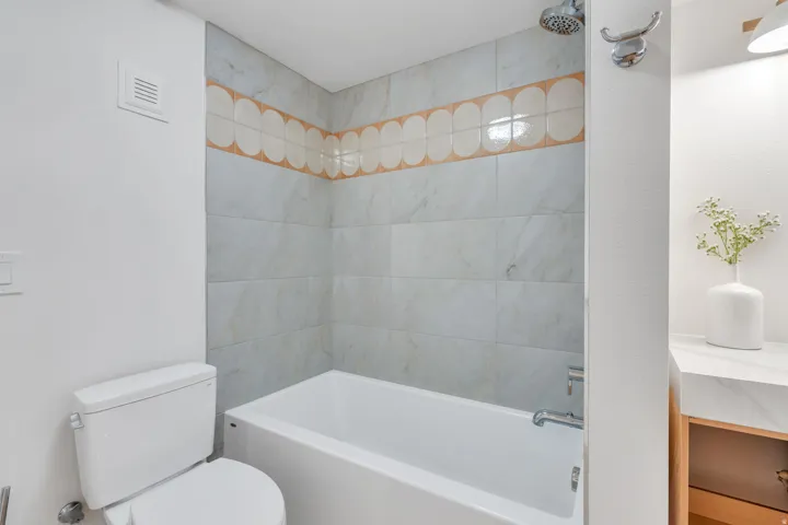 Tiled bath and shower combination with a decorative accent band and integrated shower head
