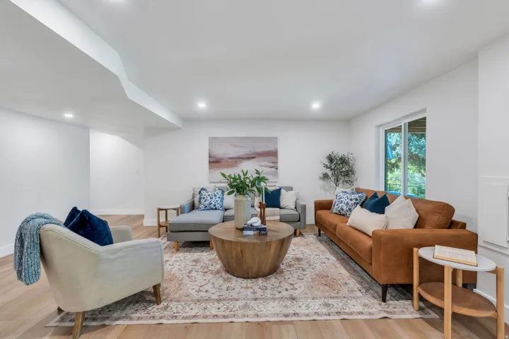Spacious living area featuring light wood-finish flooring, recessed lighting, and a large sliding glass door