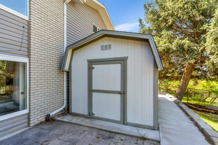 Gable-roof storage shed with white vertical siding and grey trim