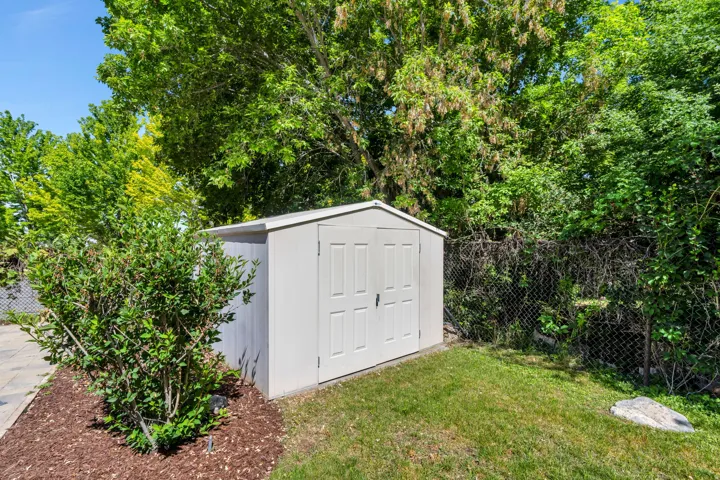 Outdoor storage shed with panel doors, situated on a grassy area