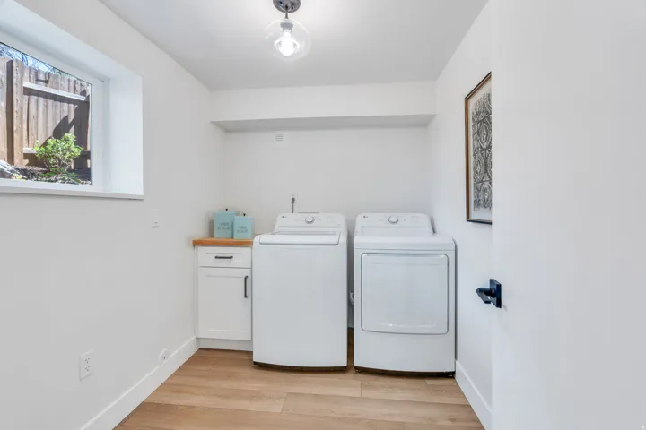 Dedicated laundry area featuring wood-finish flooring and white walls