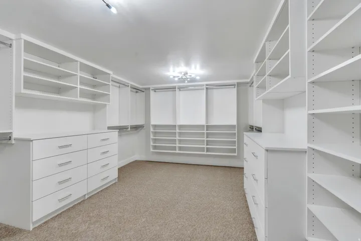 Custom closet organization system featuring white cabinetry and shelving