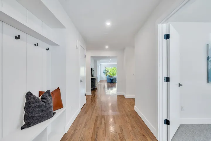 Entryway featuring built-in white shiplap bench with storage, black coat hooks, and recessed lighting