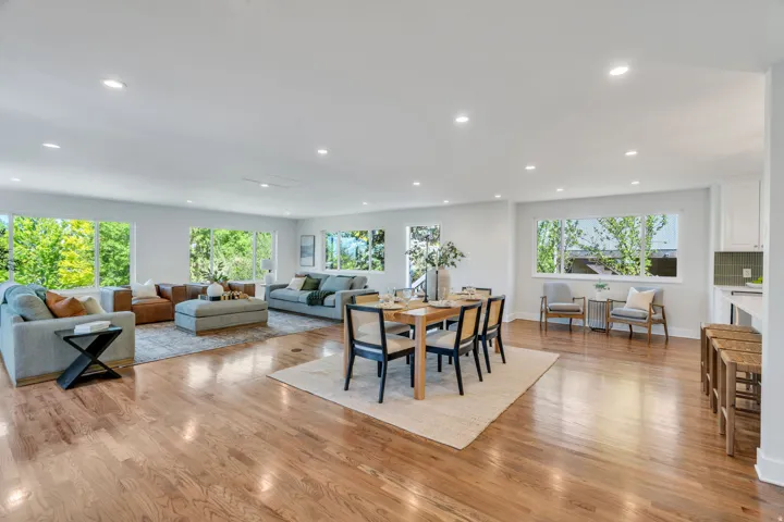 Open-concept living space featuring wood-finish flooring, recessed lighting, and multiple large windows