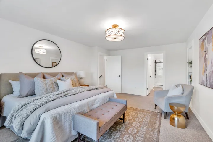 Spacious bedroom featuring carpet flooring, crisp white walls, and an ornate flush-mount ceiling light