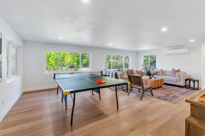 Spacious open-concept room featuring light wood-finish flooring, recessed lighting, and multiple windows