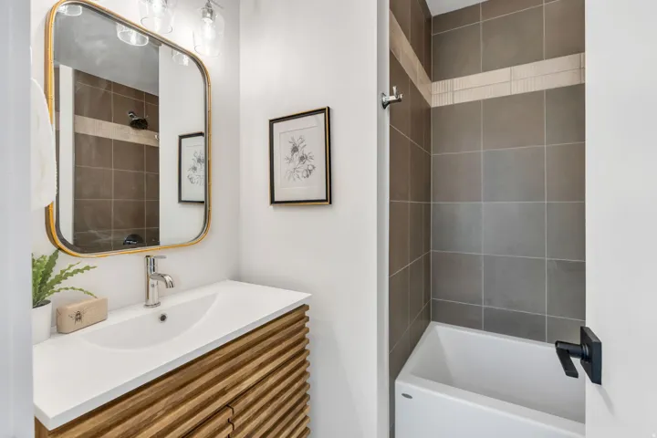 Contemporary bathroom featuring a wood-finish vanity with an integrated sink and chrome faucet