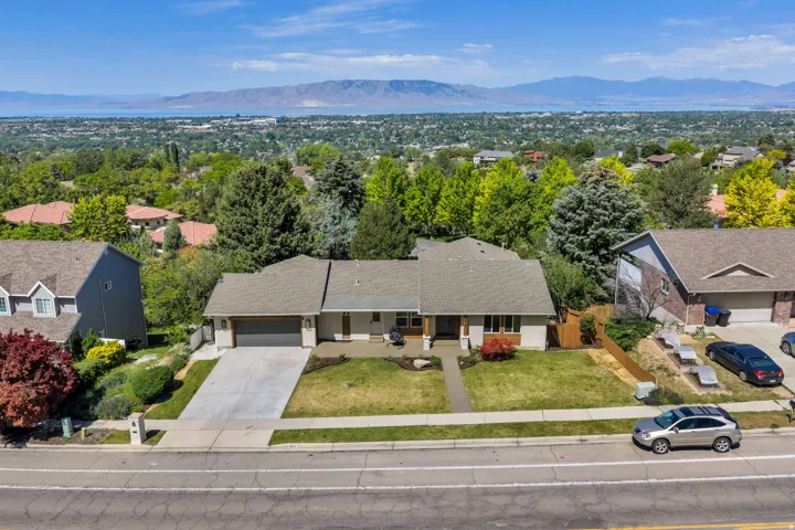 Ranch-style residence featuring a prominent shingled roof, an attached two-car garage, and a concrete driveway