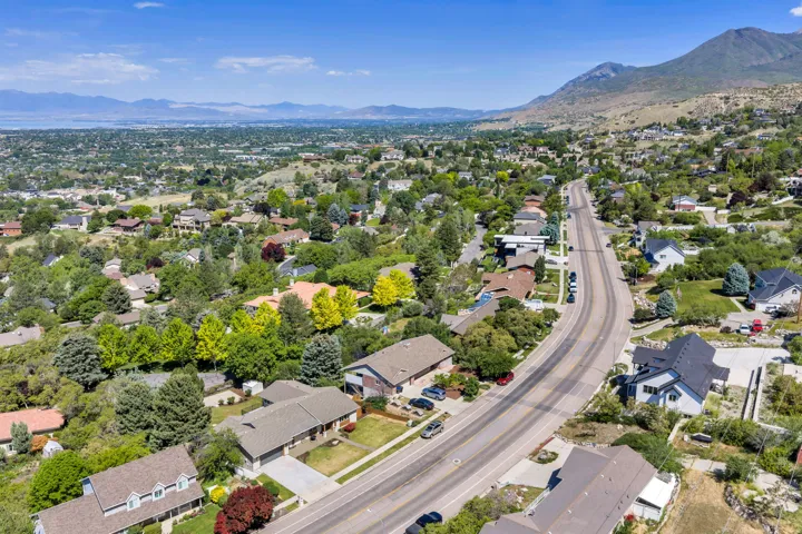 Residential neighborhood with varied architectural styles, mature trees, and a mountain backdrop