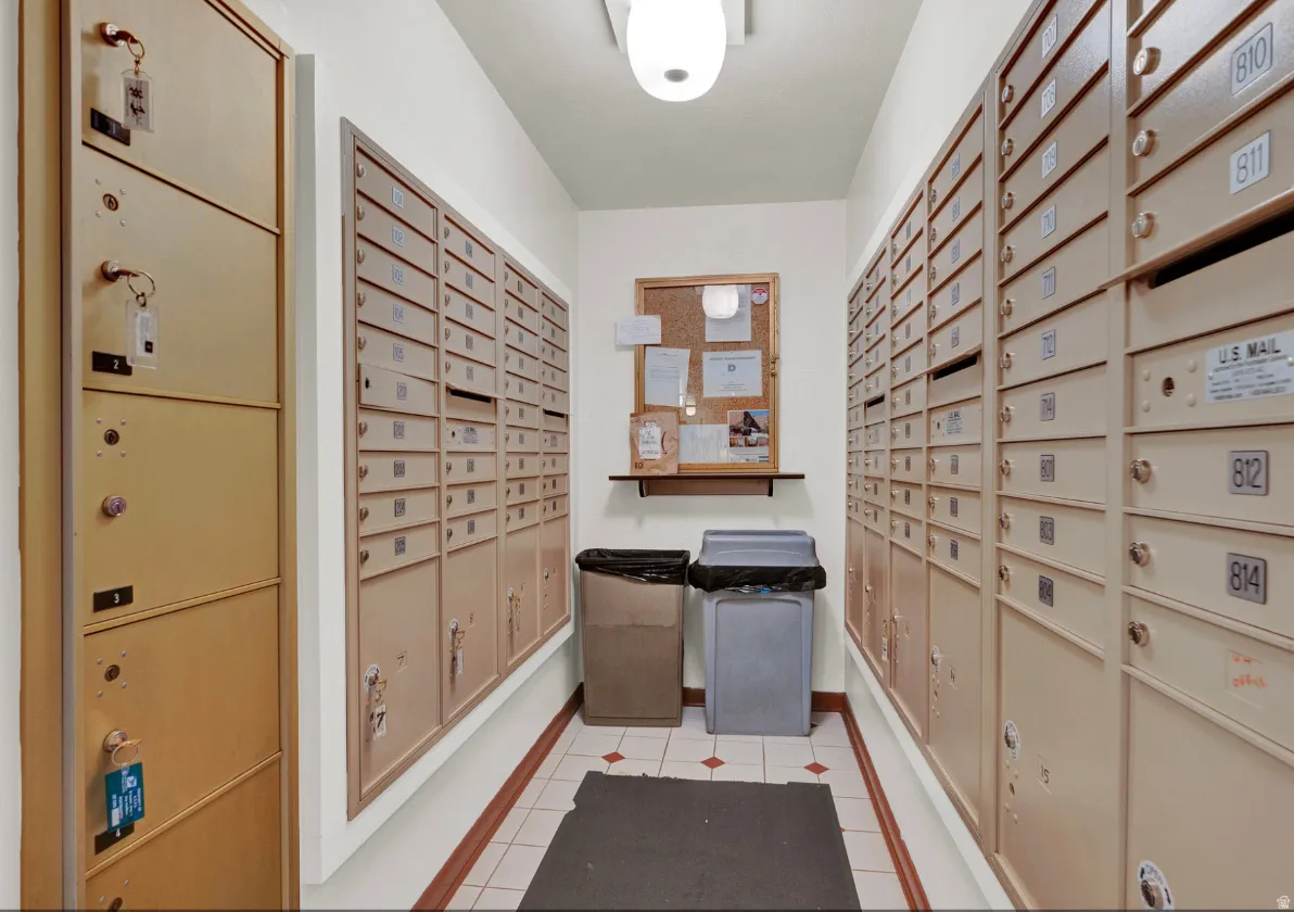 Well-lit mailroom featuring extensive wall-mounted mailboxes and a central bulletin board