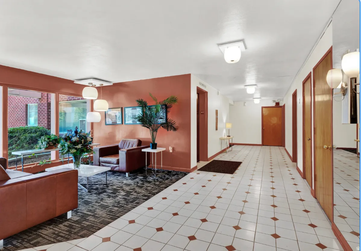 Lobby area featuring large picture windows, a modern chandelier with four pendant lights, and a patterned area rug
