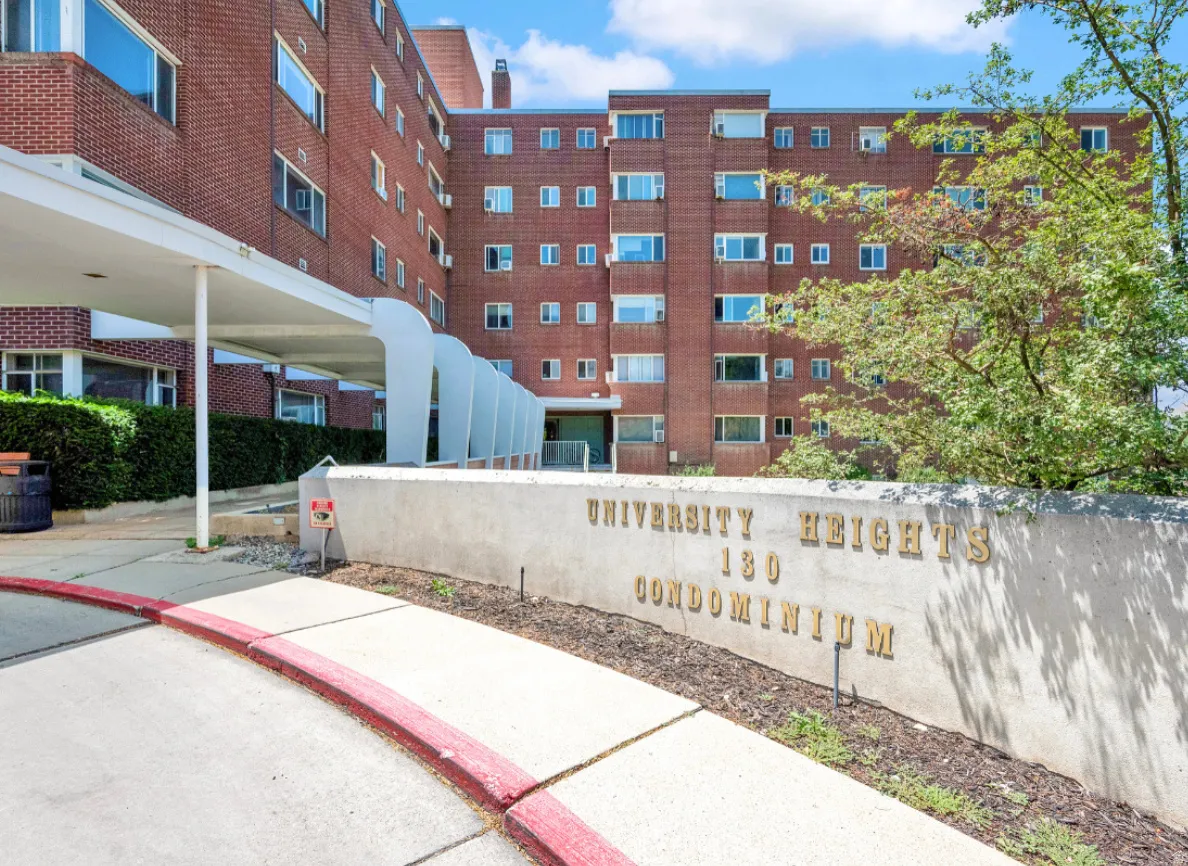 Brick condominium building featuring multiple window styles, a covered drive-up entrance, and a permanent concrete sign