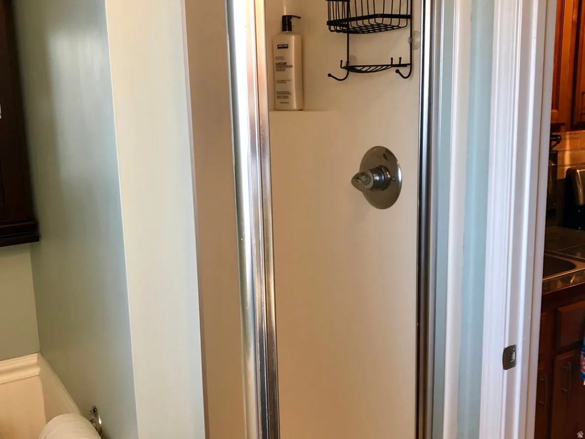 Shower stall featuring chrome framing and a single-handle temperature control