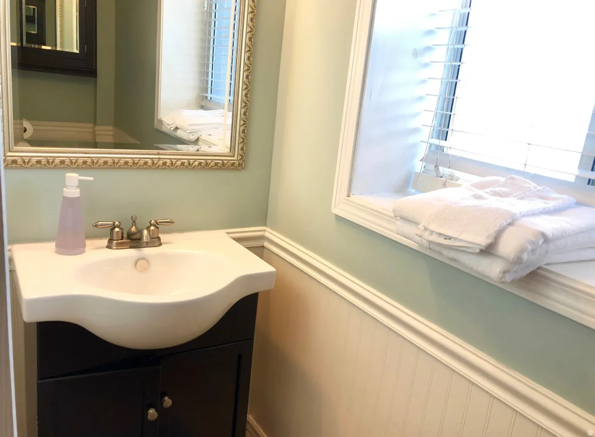 Bathroom vanity featuring a white curved sink with a brushed nickel faucet, set within a dark wood-finish cabinet