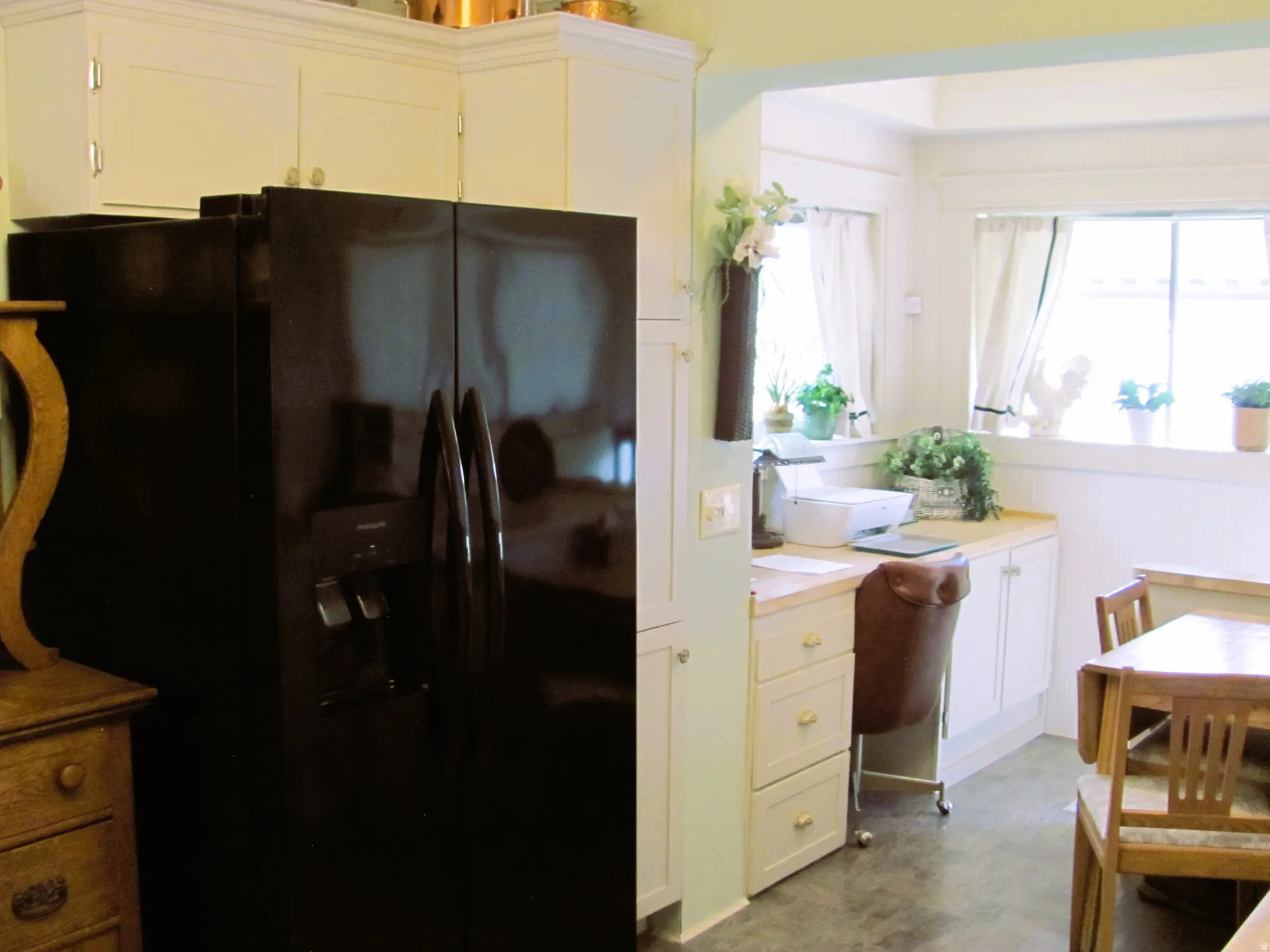Built-in desk area featuring a light wood-finish countertop, white cabinetry with drawer storage, and beadboard paneling